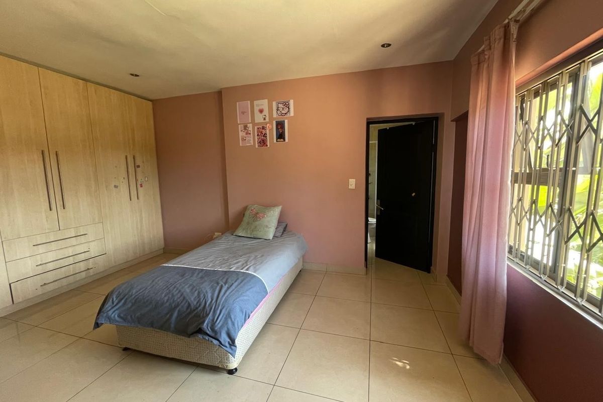 A bedroom featuring tiled flooring, built-in cupboards, and a window fitted with a security gate.