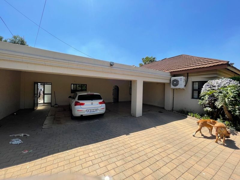 A paved driveway leading to a covered carport area with an external air conditioning unit mounted on the exterior wall.