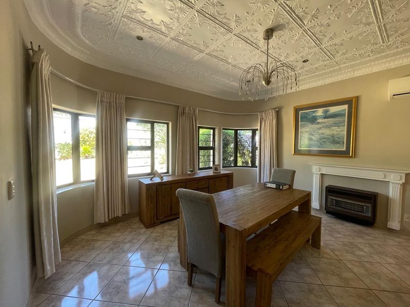 Spacious dining room featuring an ornate pressed metal ceiling, tiled flooring, and a classic fireplace mantel with a built-in gas heater.