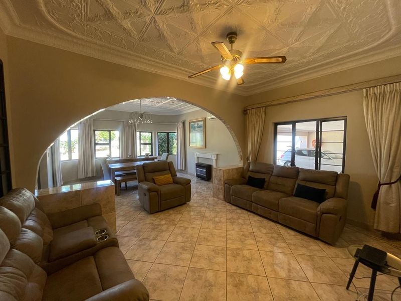 Spacious open-plan living and dining area featuring decorative ceilings, tiled flooring, a central archway, and a built-in fireplace.