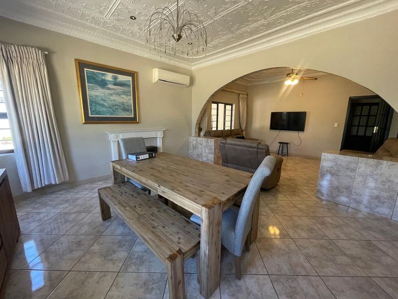 Spacious open-plan living and dining area featuring ornate ceiling detailing, tiled flooring, and a decorative fireplace mantel, creating a warm and inviting atmosphere.