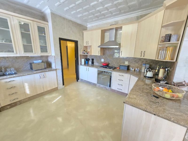 Spacious kitchen featuring light wood cabinetry, granite countertops, built-in oven, gas hob, and a decorative coffered ceiling.