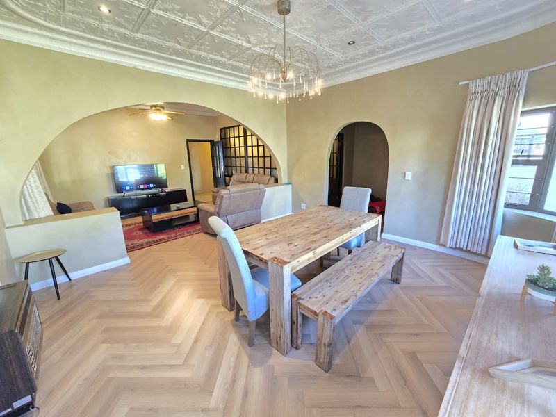 Spacious open-plan living and dining area featuring elegant herringbone timber flooring, decorative pressed metal ceilings, and distinctive architectural archways.