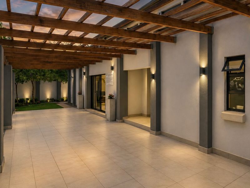 A modern covered patio featuring a timber pergola, tiled flooring, and ambient wall-mounted lighting, providing a seamless transition to the garden area.