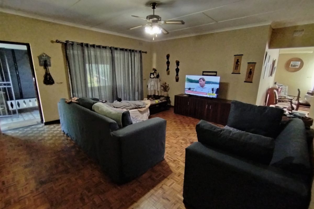 Spacious living room featuring traditional parquet flooring, a ceiling fan, and direct access to an outdoor area through sliding glass doors.
