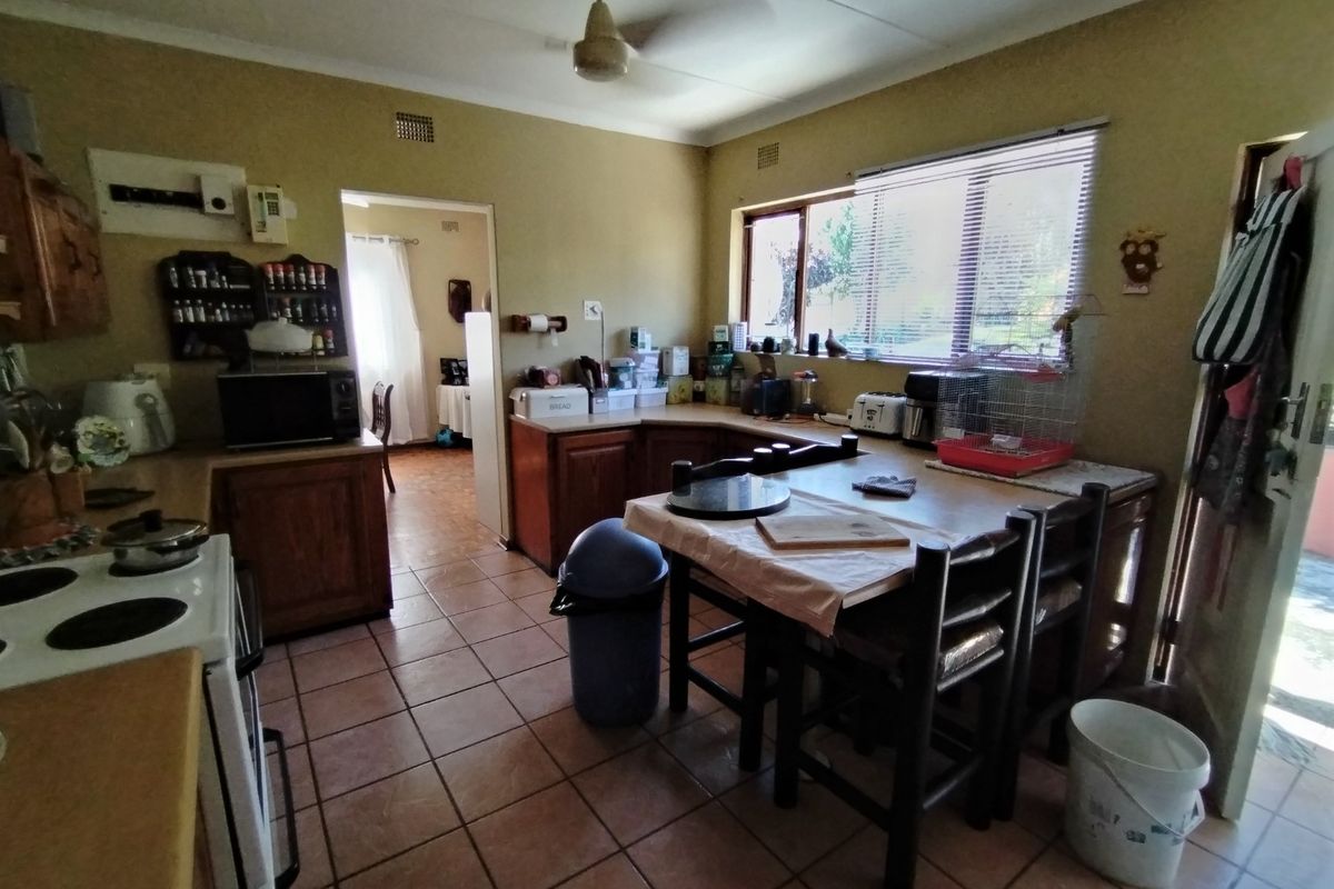A dated kitchen featuring wooden cabinetry, tiled flooring, and an electric stove, offering potential for a modern renovation.
