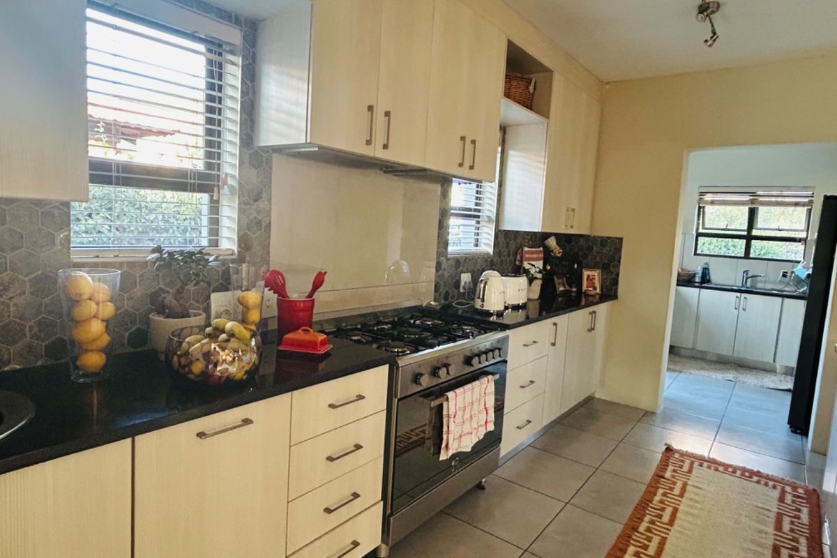 A functional kitchen featuring built-in cabinetry, granite countertops, a gas stove with oven, and a modern hexagonal tile backsplash.