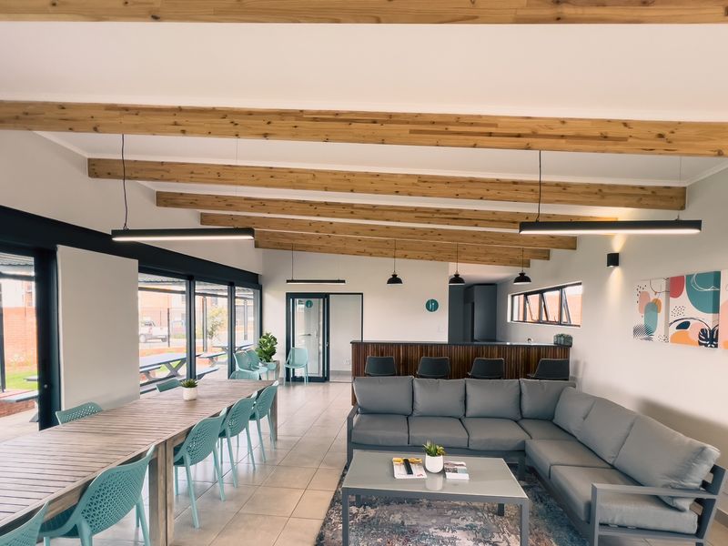 Spacious open-plan living and dining area featuring exposed timber ceiling beams, tiled flooring, and a built-in bar counter with large sliding glass doors.