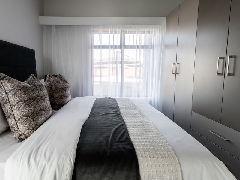 A well-maintained bedroom featuring modern built-in cupboards and a large window that allows for ample natural light.