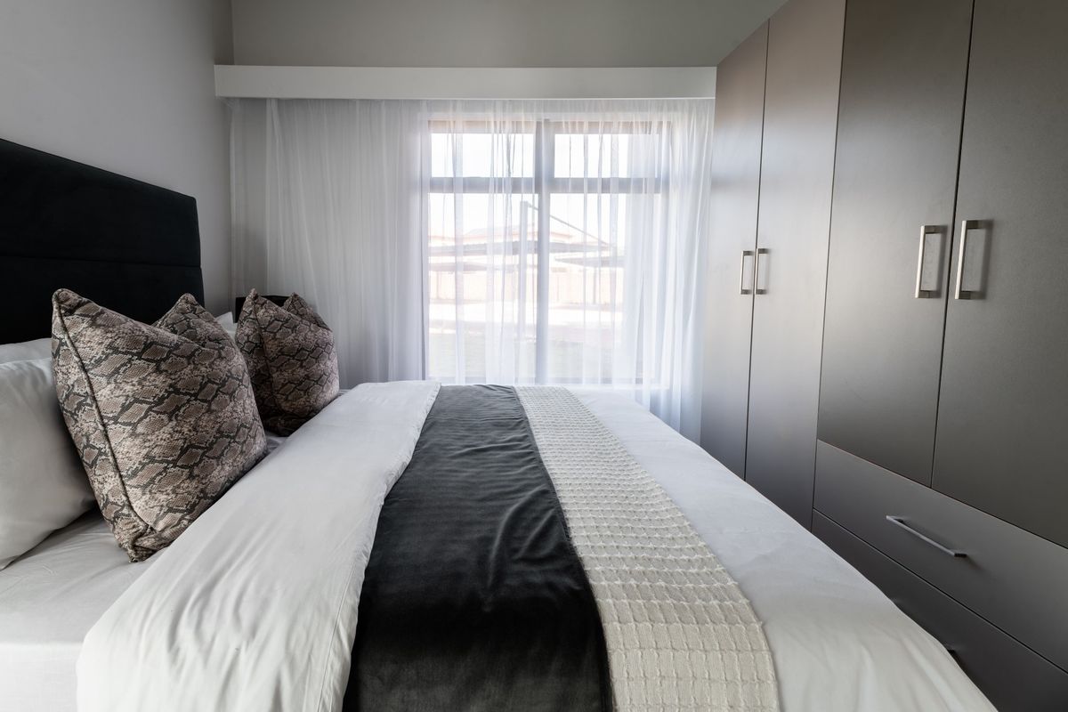 A well-maintained bedroom featuring modern built-in cupboards and a large window that allows for ample natural light.