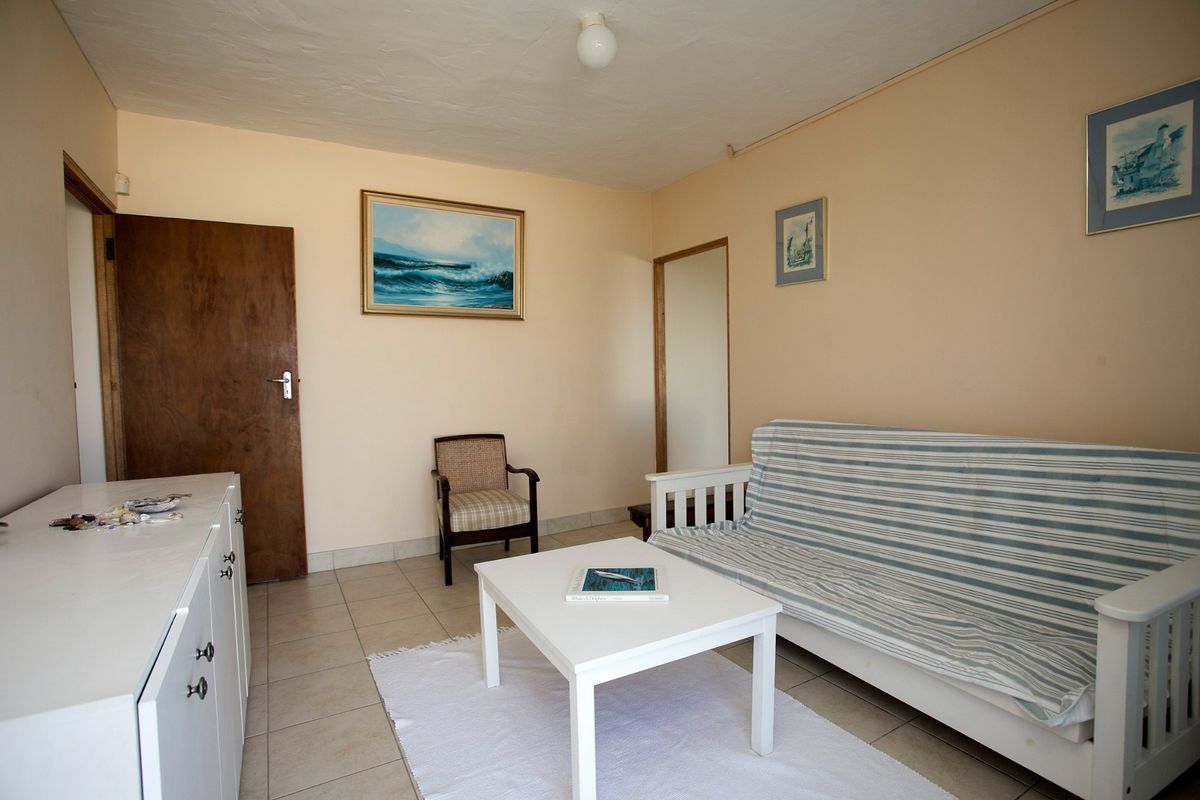 A simple living room featuring neutral wall paint and tiled flooring, providing a functional and well-lit space.