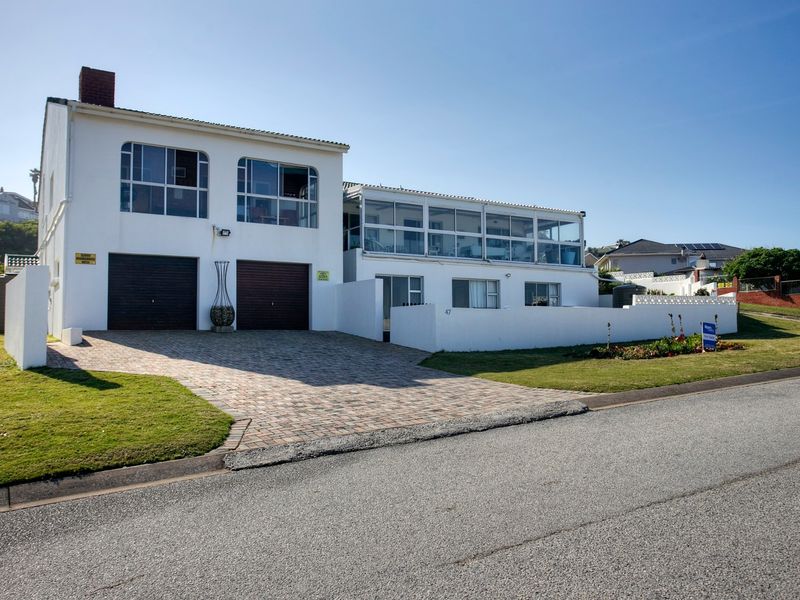 Front view of a two-story house featuring a double garage, paved driveway, and an enclosed upper-level balcony.
