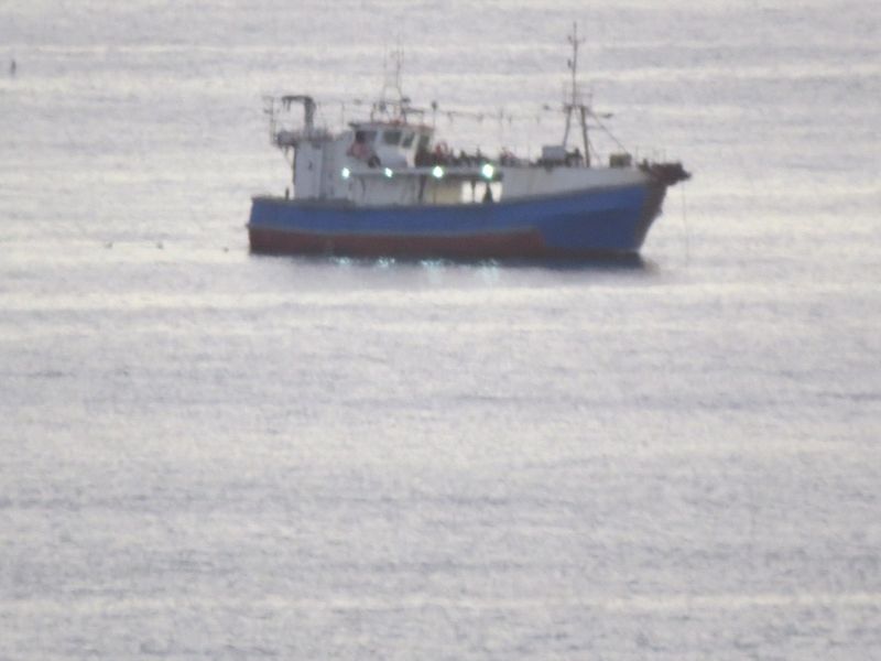 A distant view of a fishing vessel on the open water.
