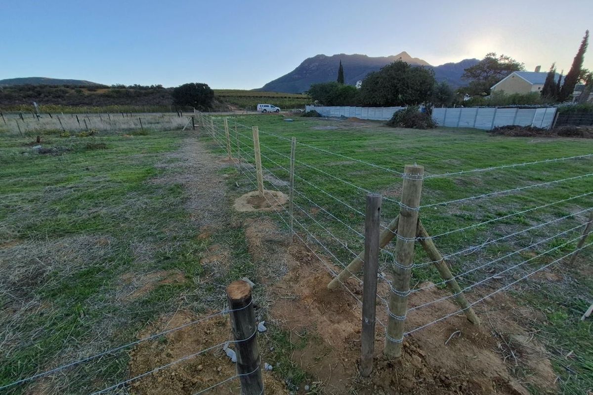 Expansive open land featuring newly installed timber and barbed wire fencing, set against a scenic mountain backdrop.