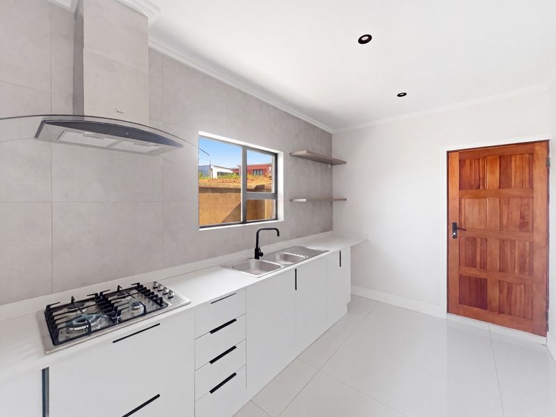 Modern, clean-lined kitchen featuring white cabinetry, gas hob, extractor fan, double sink, and sleek tiled splashback with recessed lighting.