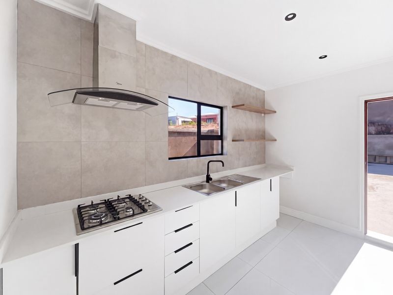 Modern kitchen featuring white cabinetry, stone countertops, a gas hob with extractor fan, and a double sink with a sleek black mixer tap.