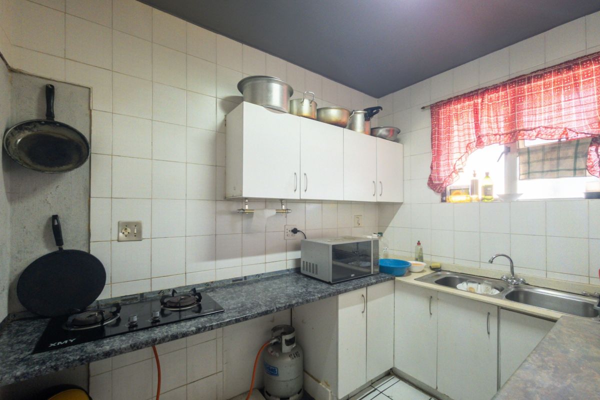 A functional kitchen featuring built-in cabinetry, a gas hob, and a stainless steel sink with tiled backsplash throughout.