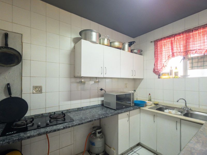 A functional kitchen featuring built-in cabinetry, a gas hob, and a stainless steel sink with tiled backsplash throughout.