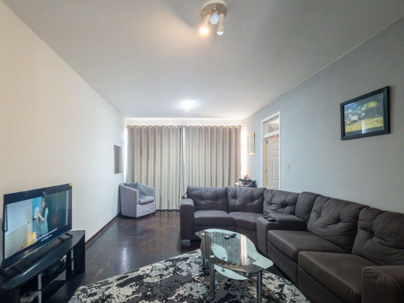A spacious living room featuring dark wood flooring and neutral wall tones, providing a comfortable and functional area for relaxation.