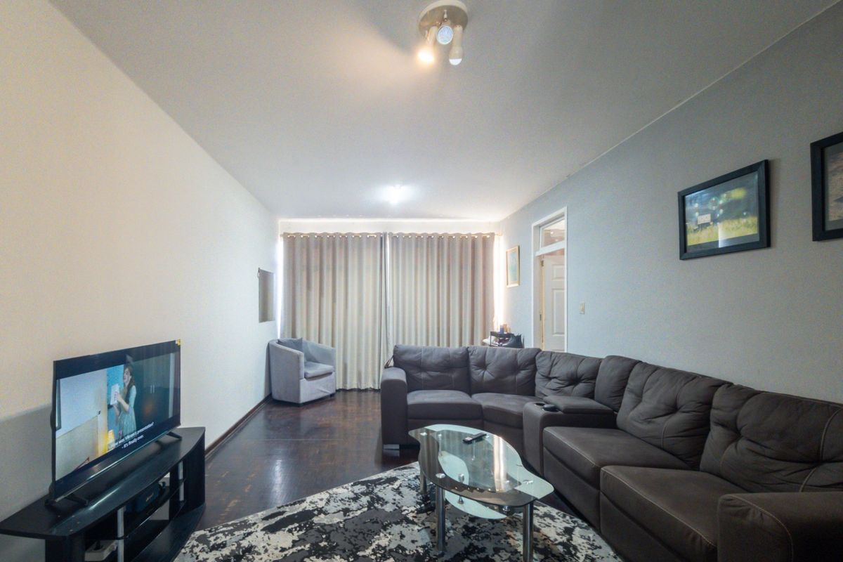 A spacious living room featuring dark wood flooring and neutral wall tones, providing a comfortable and functional area for relaxation.
