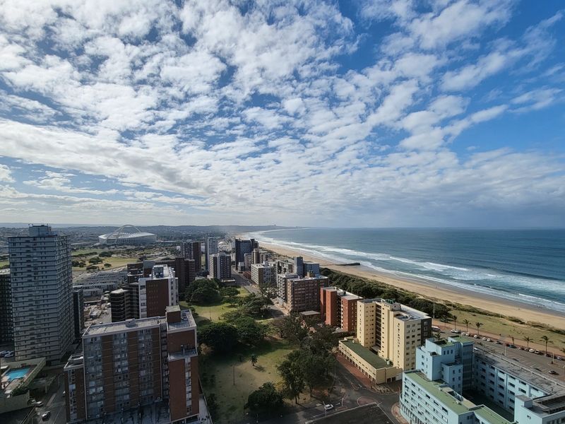 Elevated panoramic coastal view overlooking the city skyline, beach, and ocean.