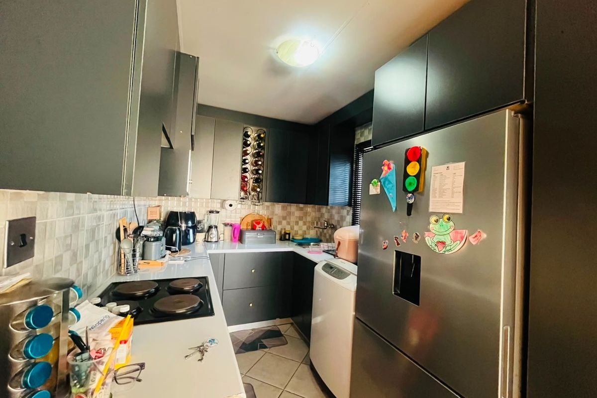 A compact kitchen featuring dark cabinetry, a tiled backsplash, and an electric hob, providing a functional workspace with integrated storage solutions.
