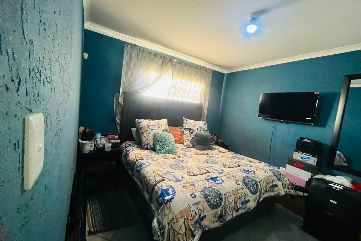 A bedroom featuring tiled flooring, security window bars, and blue painted walls with cove cornicing.