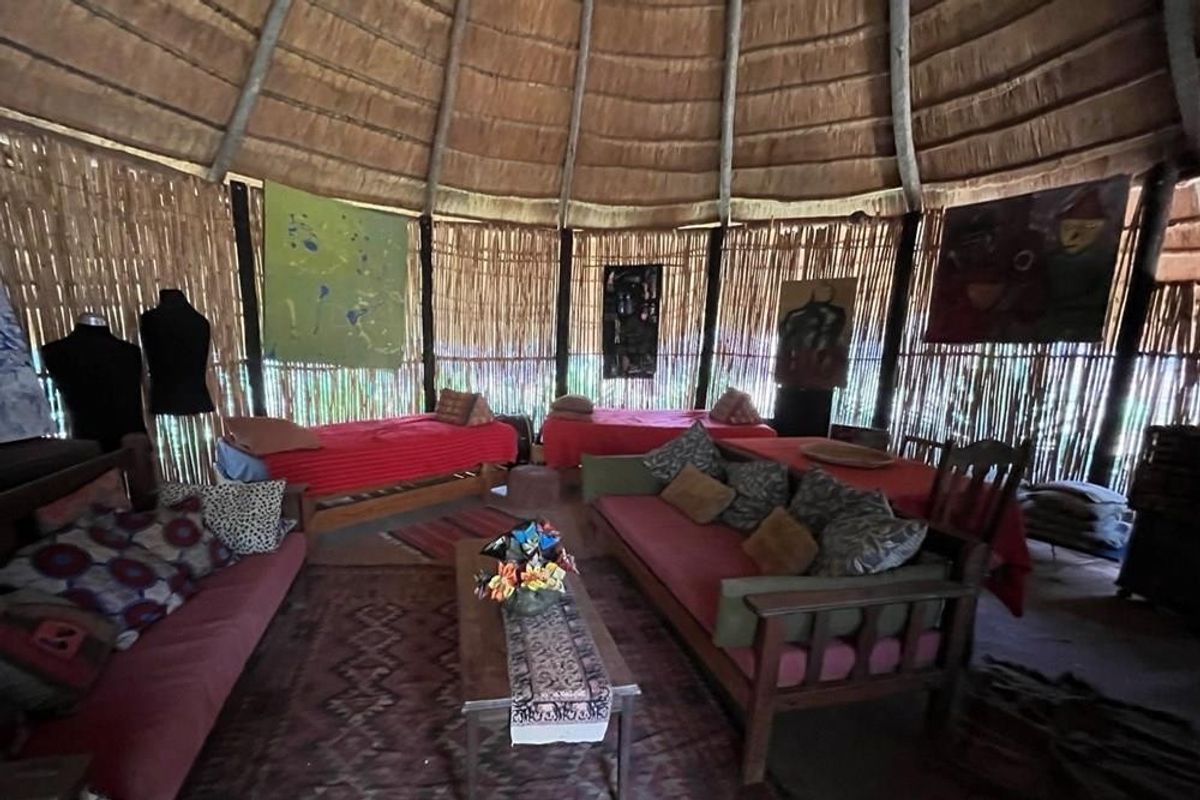A rustic living area featuring a traditional thatched roof with exposed timber rafters and natural reed wall cladding, creating a unique farm-style atmosphere.