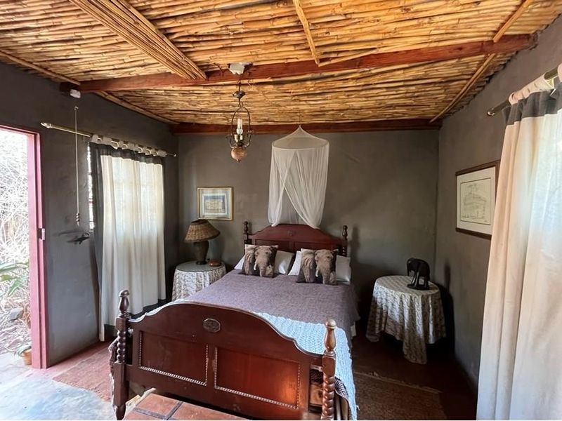 A rustic bedroom featuring a unique exposed reed ceiling with timber beams and plastered walls, offering a cozy and authentic farm-style atmosphere.