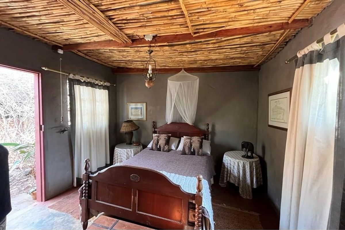 A rustic bedroom featuring a unique exposed reed ceiling with timber beams and plastered walls, offering a cozy and authentic farm-style atmosphere.