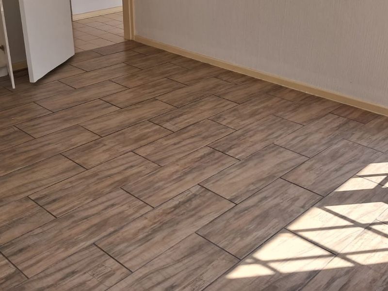 An empty bedroom featuring wood-look tiled flooring, built-in cupboard storage, and visible electrical points.