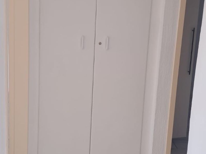 A functional hallway featuring tiled flooring and a built-in storage cupboard, providing clean and simple circulation space within the apartment.