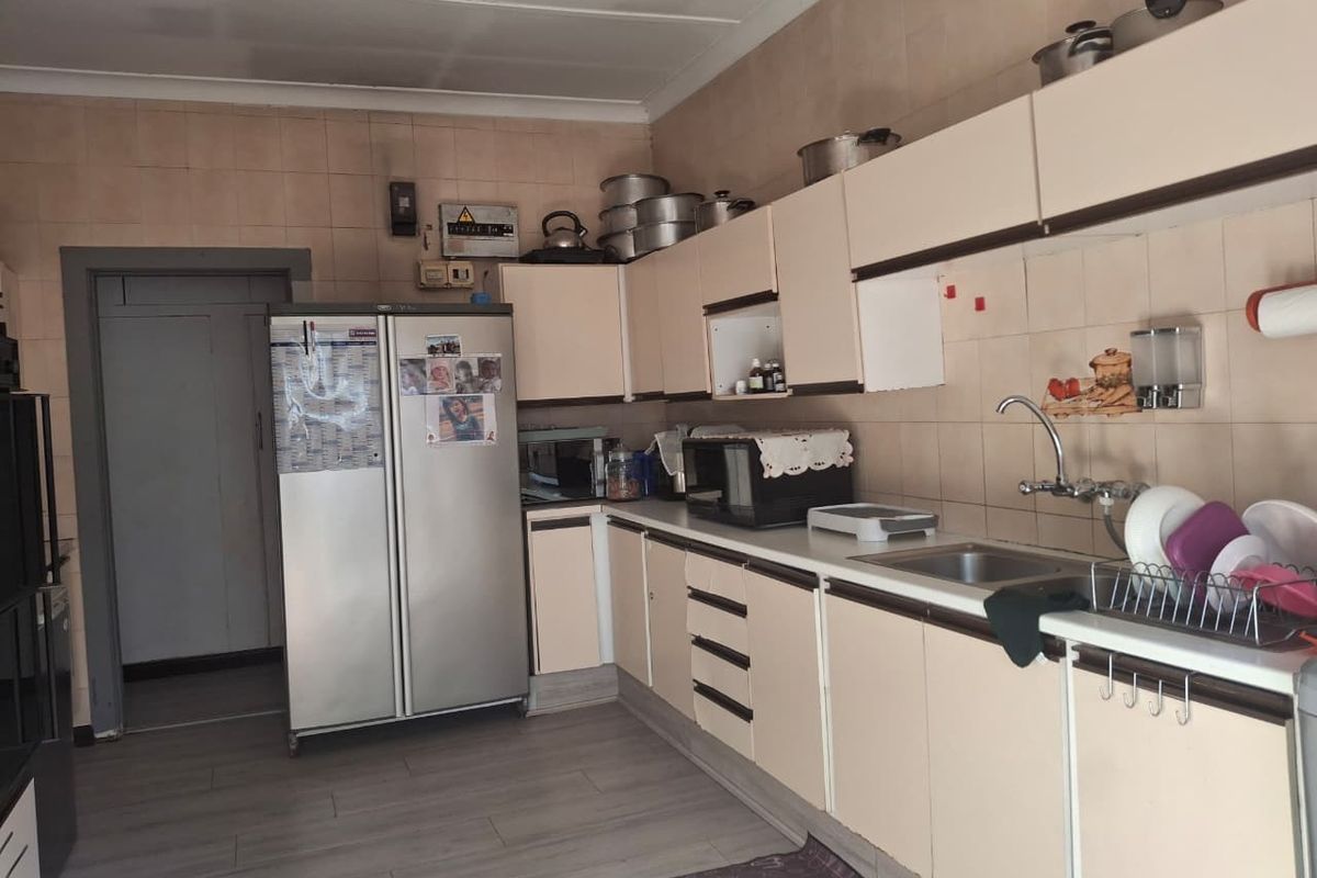 A dated kitchen featuring built-in cabinetry, laminate countertops, and a stainless steel sink, with visible signs of wear and ceiling water damage.