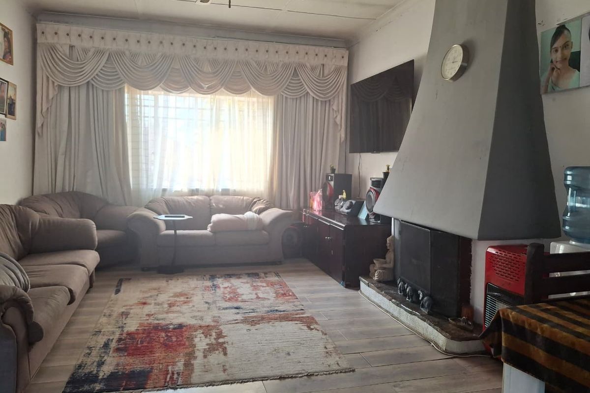 A living room featuring a prominent fireplace, ceiling fan, and laminate flooring, offering a comfortable space for relaxation.