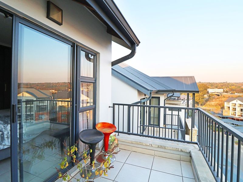A private balcony featuring tiled flooring, a metal balustrade, and large sliding glass doors providing access to the interior.
