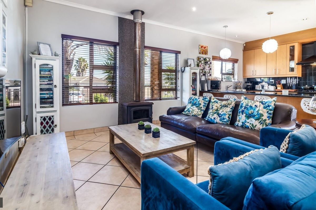 Open-plan living area featuring a central freestanding fireplace, tiled flooring, and a functional kitchen with granite countertops and ample cabinetry.