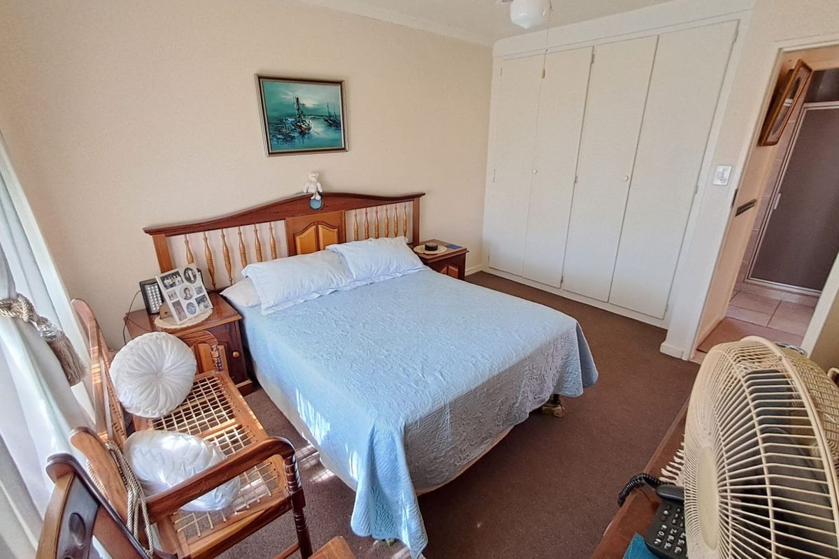 A carpeted bedroom featuring built-in cupboards and a ceiling fan, offering a functional and well-maintained living space.
