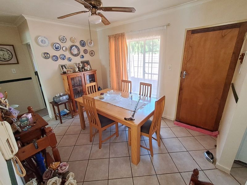 A functional dining area featuring tiled flooring, a ceiling fan, and direct access to the exterior via a sliding glass door.
