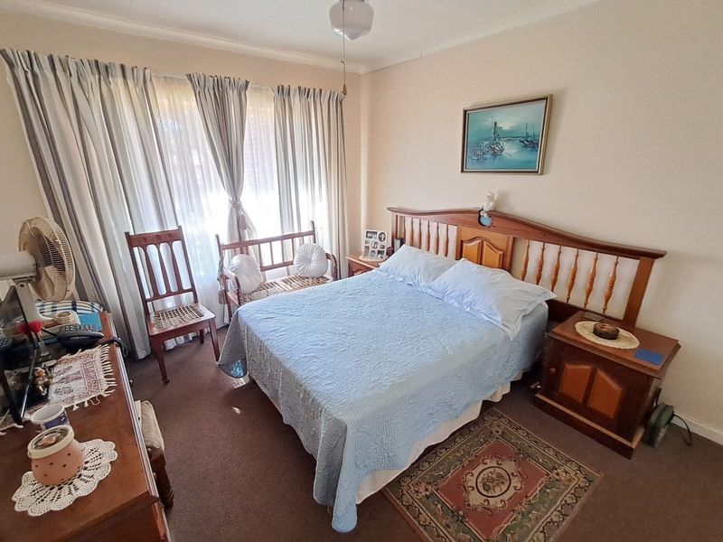 A standard bedroom featuring carpeted flooring, neutral wall finishes, and large window treatments, offering a functional and comfortable living space.