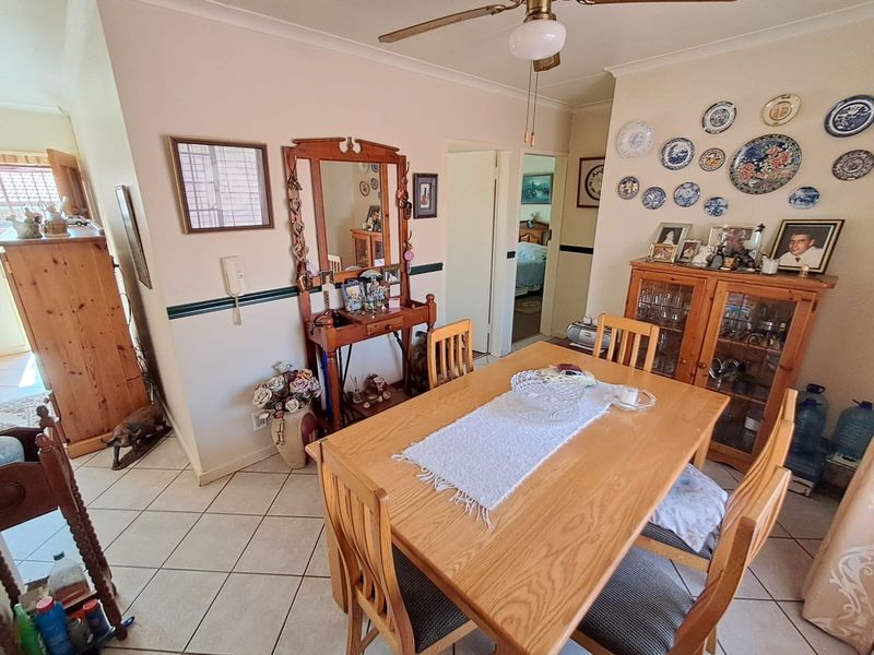 A dining room featuring tiled flooring, a ceiling fan, and decorative wall molding, providing a functional space for family meals.