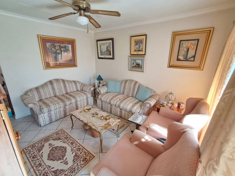 A comfortable living room featuring tiled flooring and a ceiling fan, providing a functional space for relaxation.