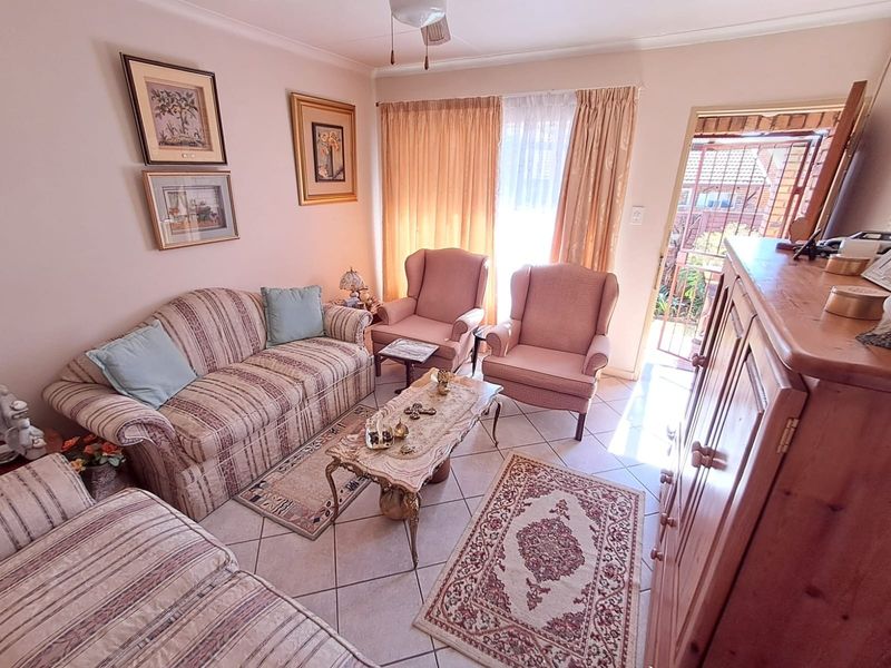 A cozy living room featuring tiled flooring and direct access to an outdoor area through a sliding glass door with a security gate.