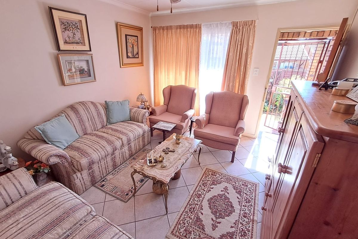 A cozy living room featuring tiled flooring and direct access to an outdoor area through a sliding glass door with a security gate.