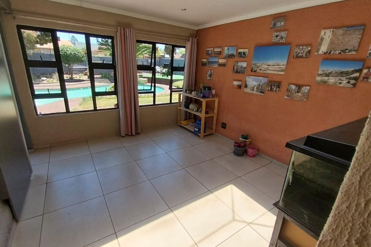A bright living area featuring large windows with views of the pool, tiled flooring, and neutral wall finishes.