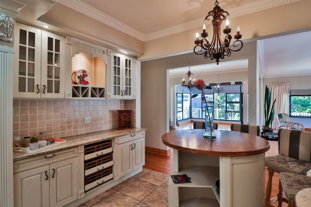 A well-appointed kitchen featuring classic cabinetry, stone countertops, and a central island, flowing into an adjacent living area with hardwood floors.