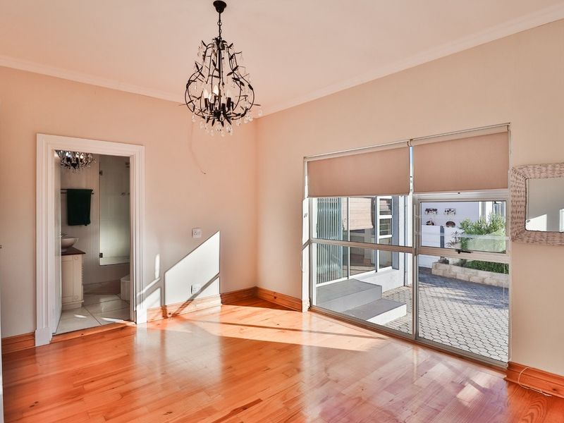 Bright and spacious bedroom featuring polished hardwood flooring, large sliding glass doors with roller blinds, and direct access to an en-suite bathroom.