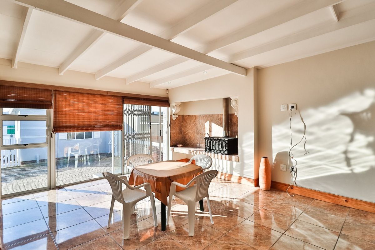 Spacious living area featuring tiled flooring, exposed beam ceilings, and a built-in fireplace, with direct access to the outdoor patio through sliding glass doors.