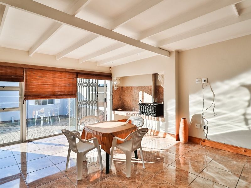 Spacious living area featuring tiled flooring, exposed beam ceilings, and a built-in fireplace, with direct access to the outdoor patio through sliding glass doors.