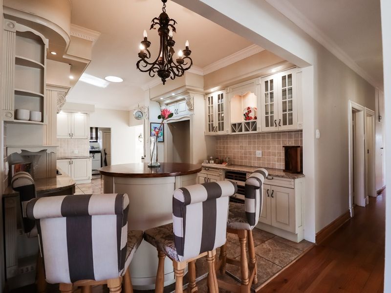 A well-appointed kitchen featuring classic cabinetry, stone countertops, a central island, and elegant lighting, seamlessly transitioning into the adjacent living area.