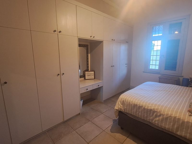 Bedroom featuring extensive floor-to-ceiling built-in cupboards with an integrated vanity station and tiled flooring.